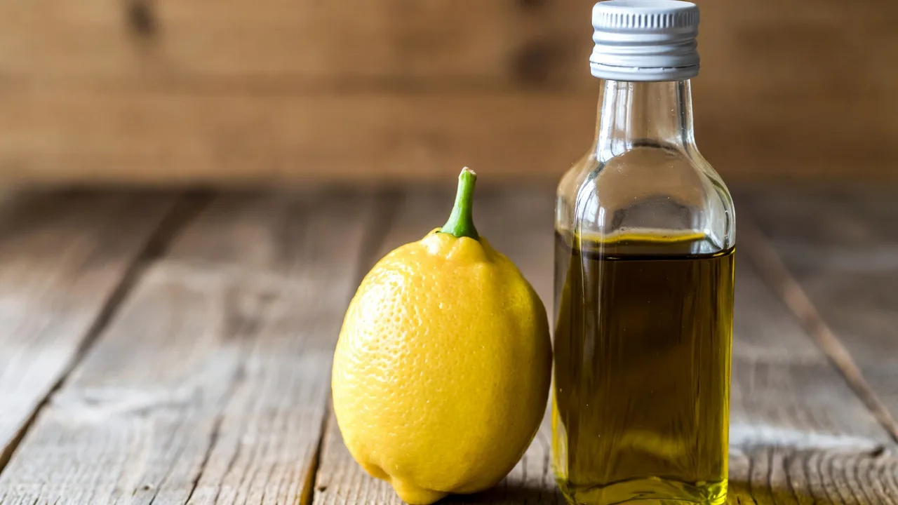 Lemon olive oil in glass bottle with fresh lemons and olive branches