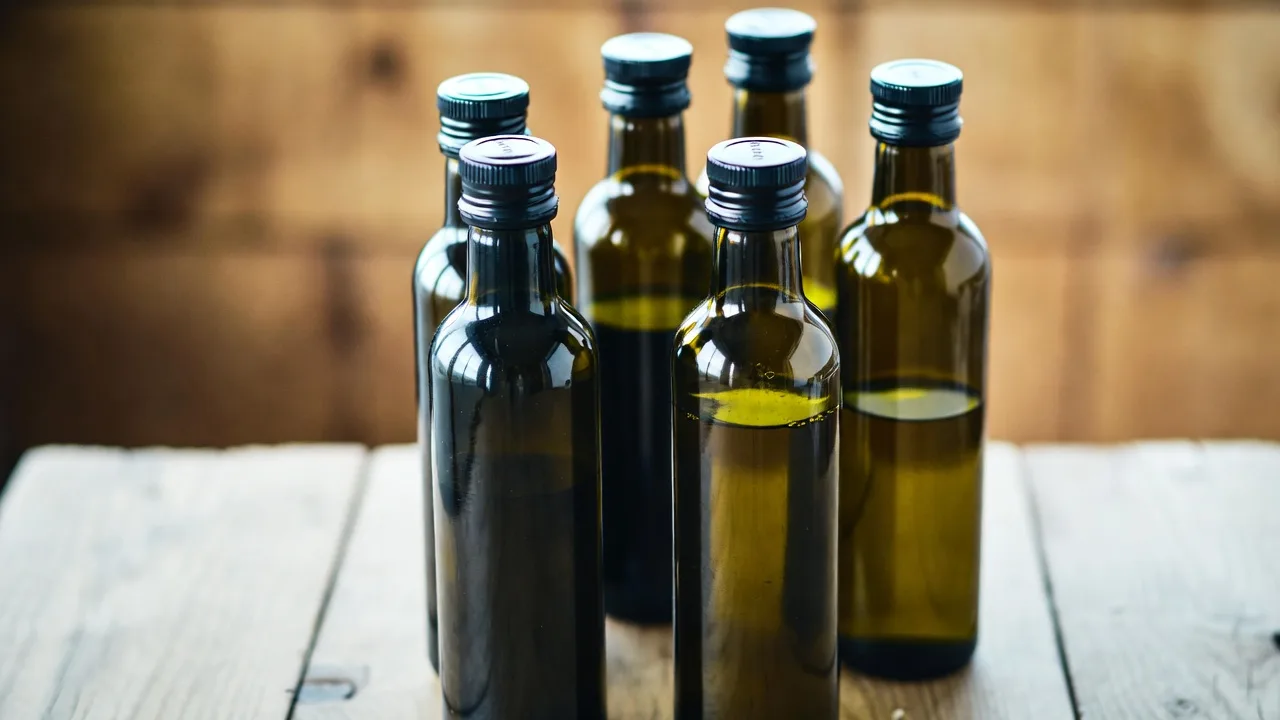Various olive oil bottles displayed on a wooden table with Mediterranean decor